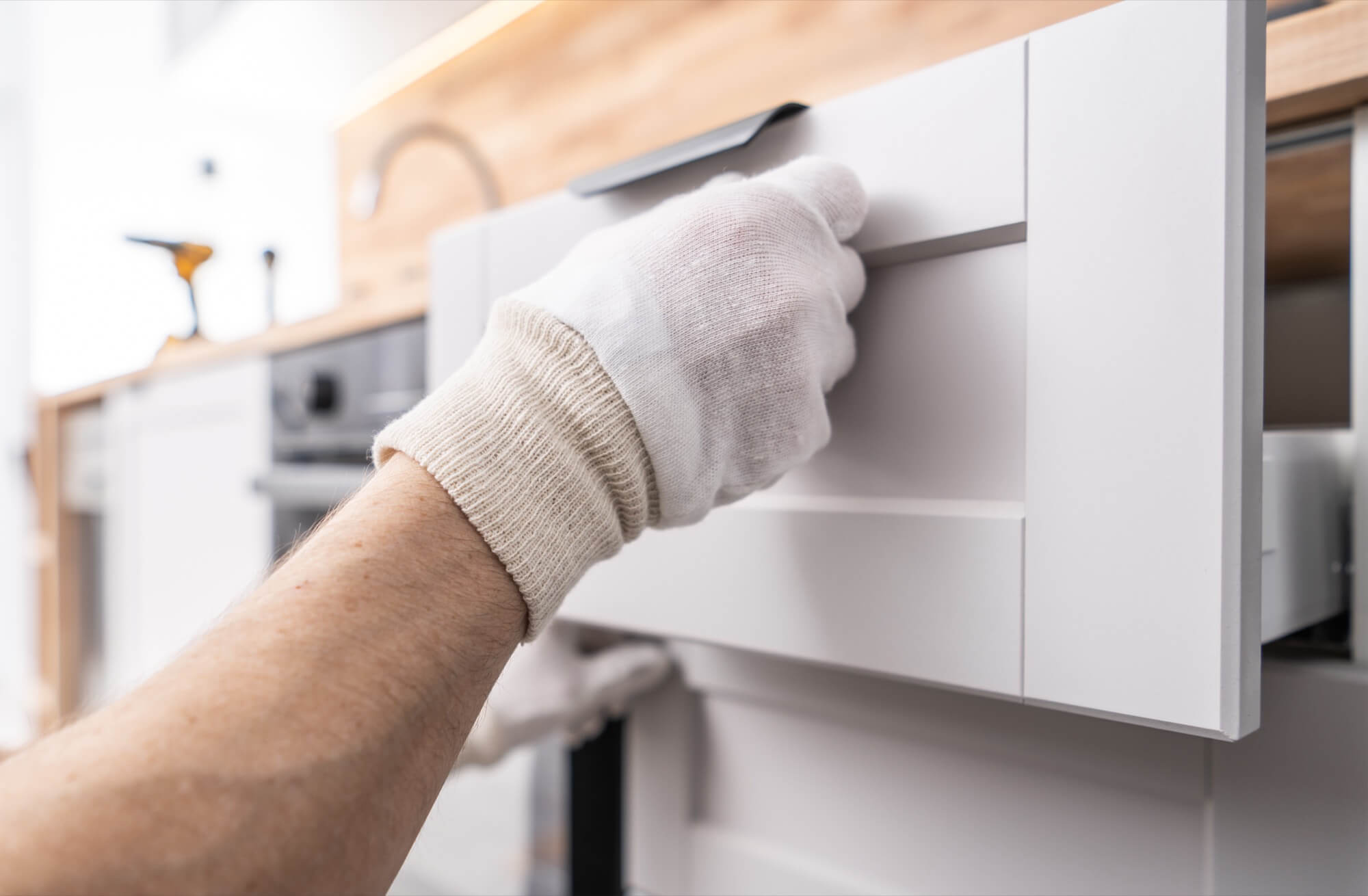 A craftsman checks the functionality of a newly installed kitchen drawer after a successful kitchen renovation.